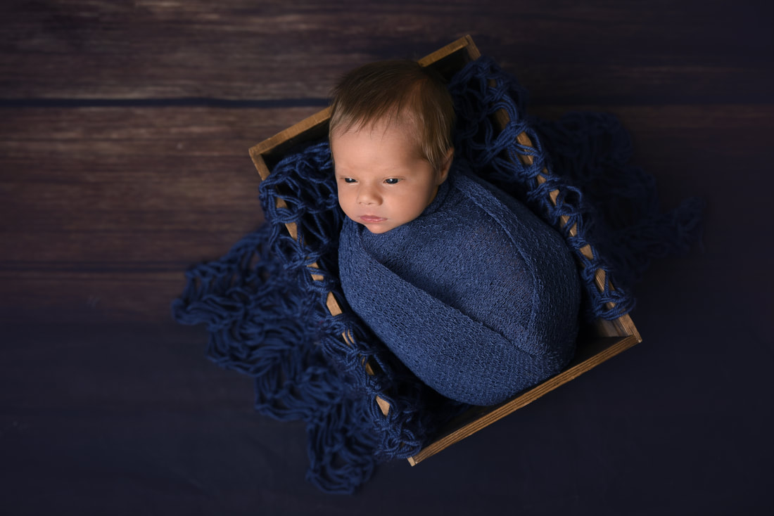 awake newborn baby boy wrapped in blue