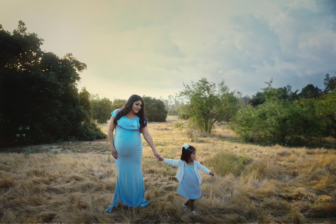 Mama-to-be and big sister outside in a baby blue maternity gown 